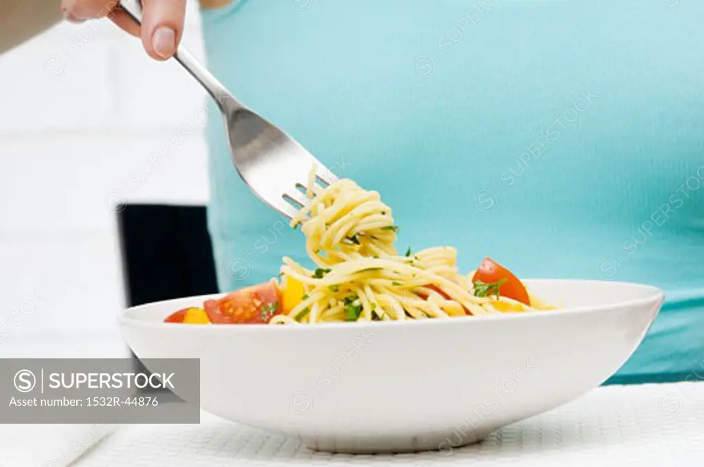 Wrapping spaghetti with herbs and vegetables round fork