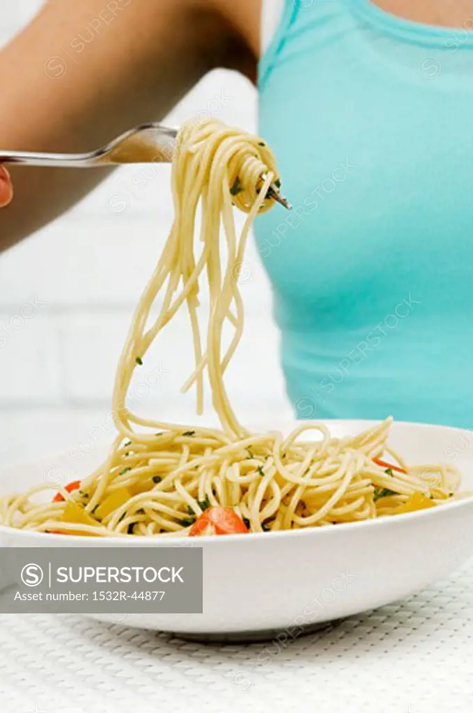 Spaghetti with herbs and vegetables wrapped round a fork