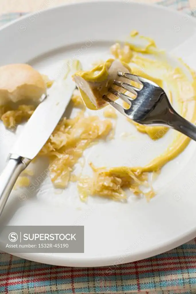 Remains of sausage with sauerkraut, mustard and bread roll