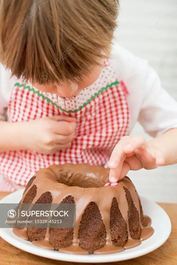 Small boy decorating ring cake with coloured chocolate beans