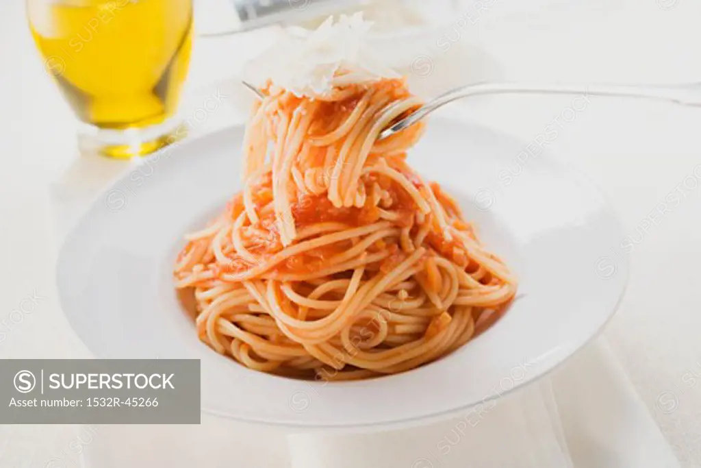 Spaghetti with tomato sauce and Parmesan on fork and plate