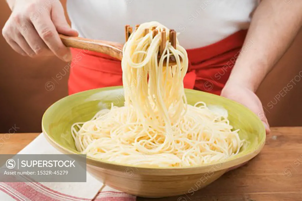 Picking up cooked spaghetti with spaghetti server