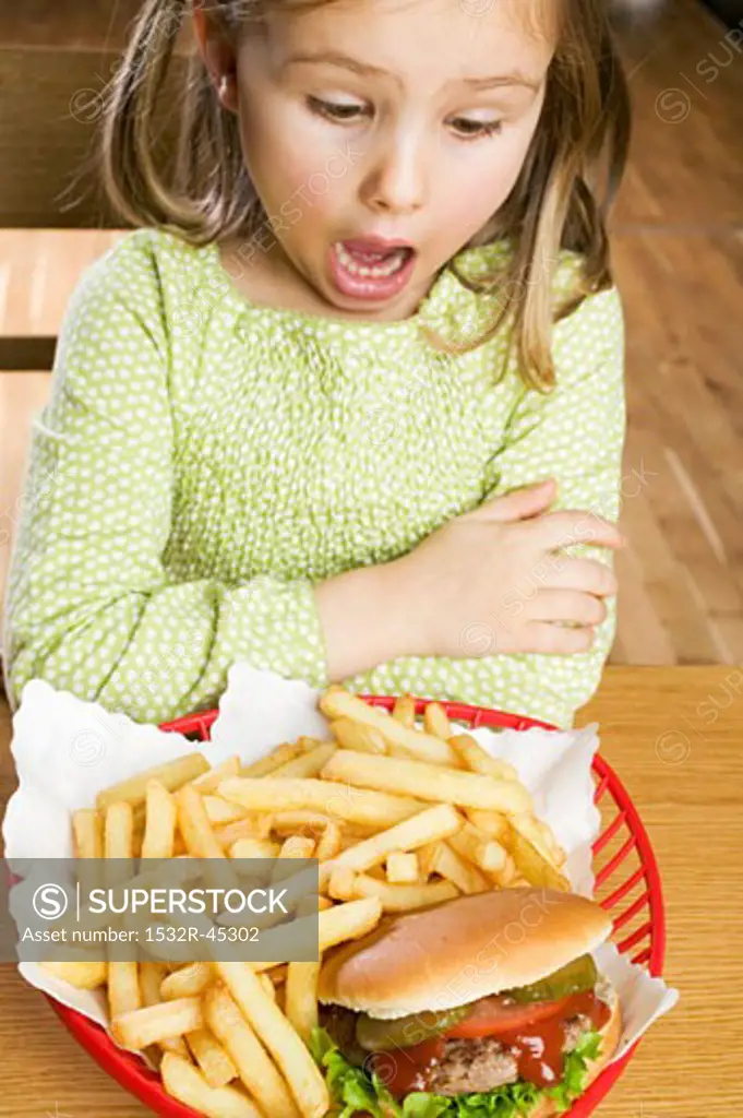 Horrified girl looking at hamburger and chips