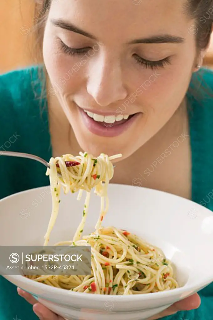 Young woman eating spaghetti with chillies