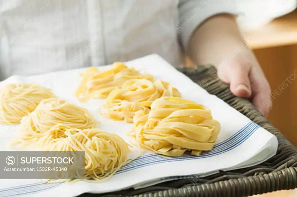 Person holding home-made pasta on wicker tray