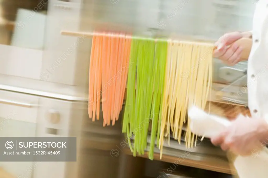 Chef hurrying through kitchen with ribbon pasta on wooden spoon