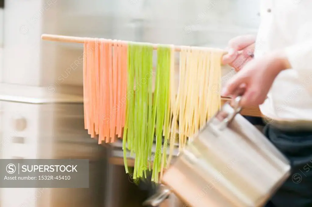 Chef hurrying through kitchen with ribbon pasta on wooden spoon