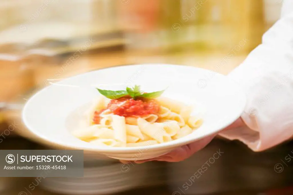 Chef serving penne with tomato sauce