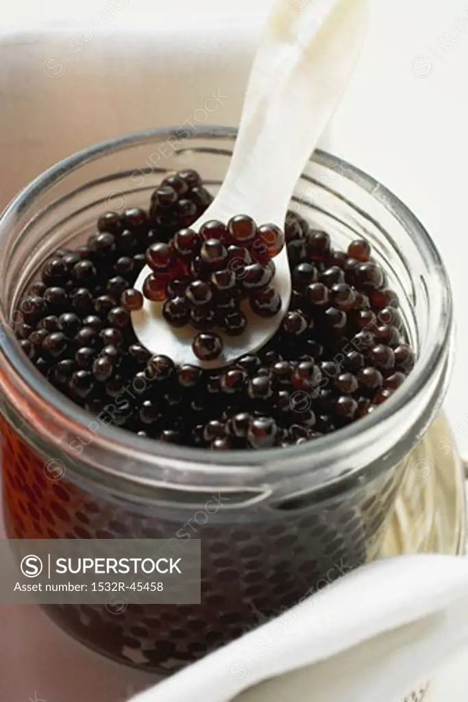 Black caviar in jar with mother-of-pearl spoon