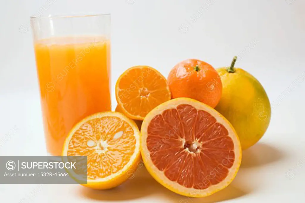 Glass of fruit juice and fresh citrus fruit