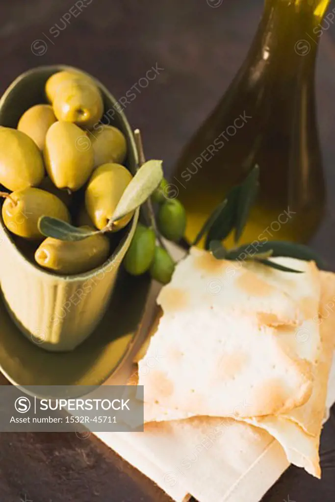 Green olives in bowl, crackers beside it