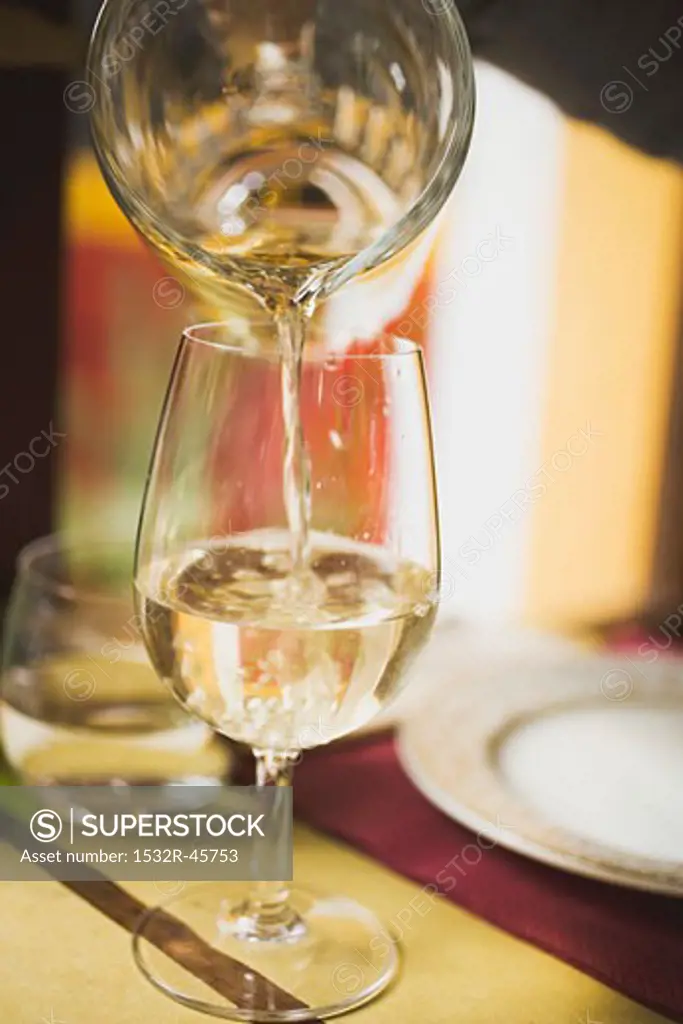 Pouring white wine from carafe into glass