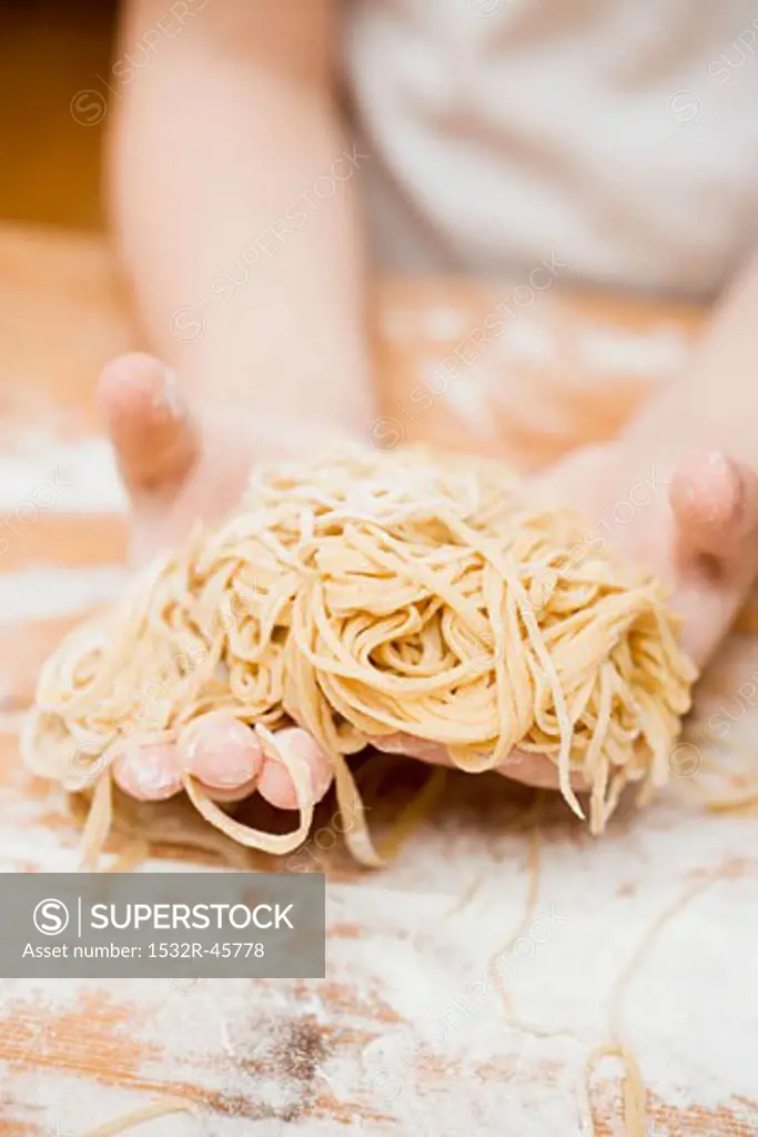 Child's hands holding home-made linguine