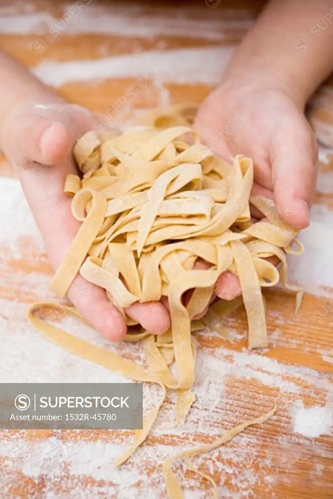 Child's hands holding home-made ribbon pasta