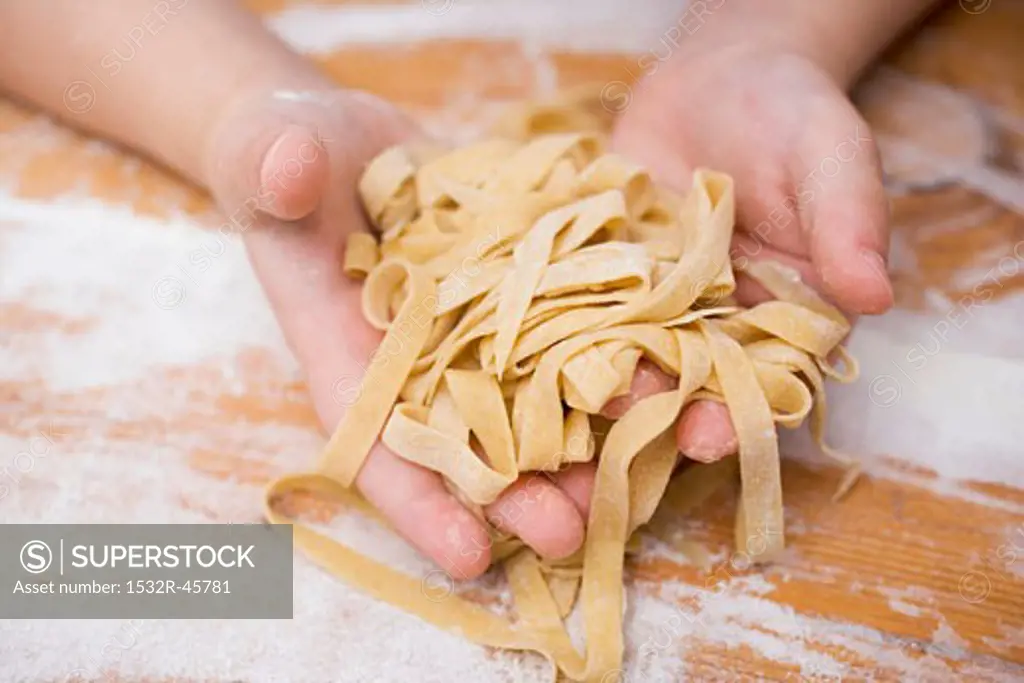 Child's hands holding home-made ribbon pasta