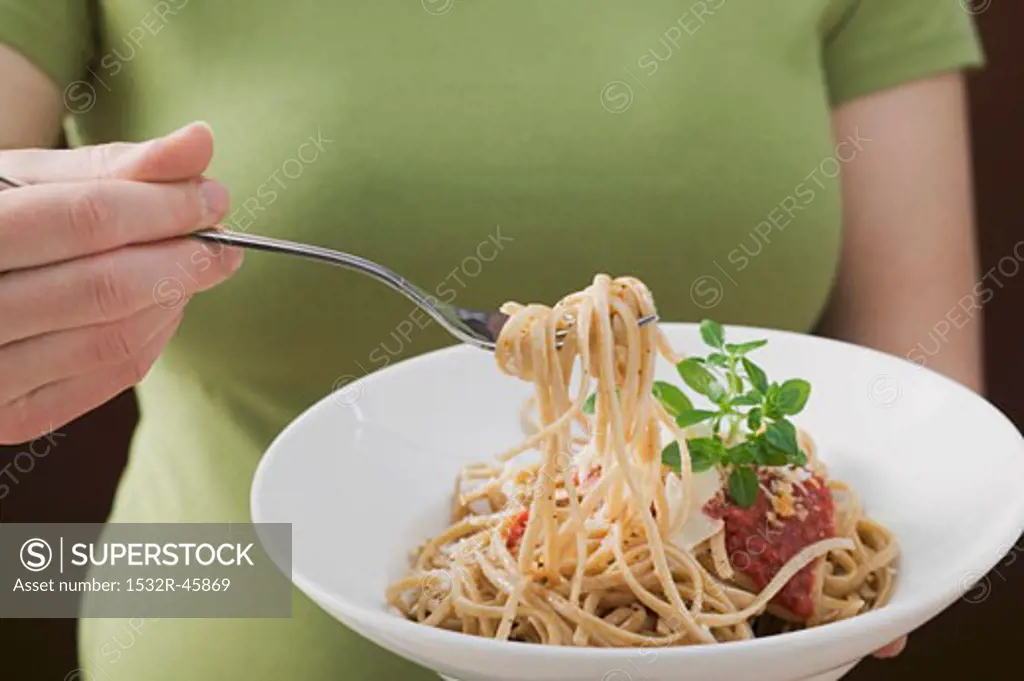 Woman eating linguine with tomato sauce