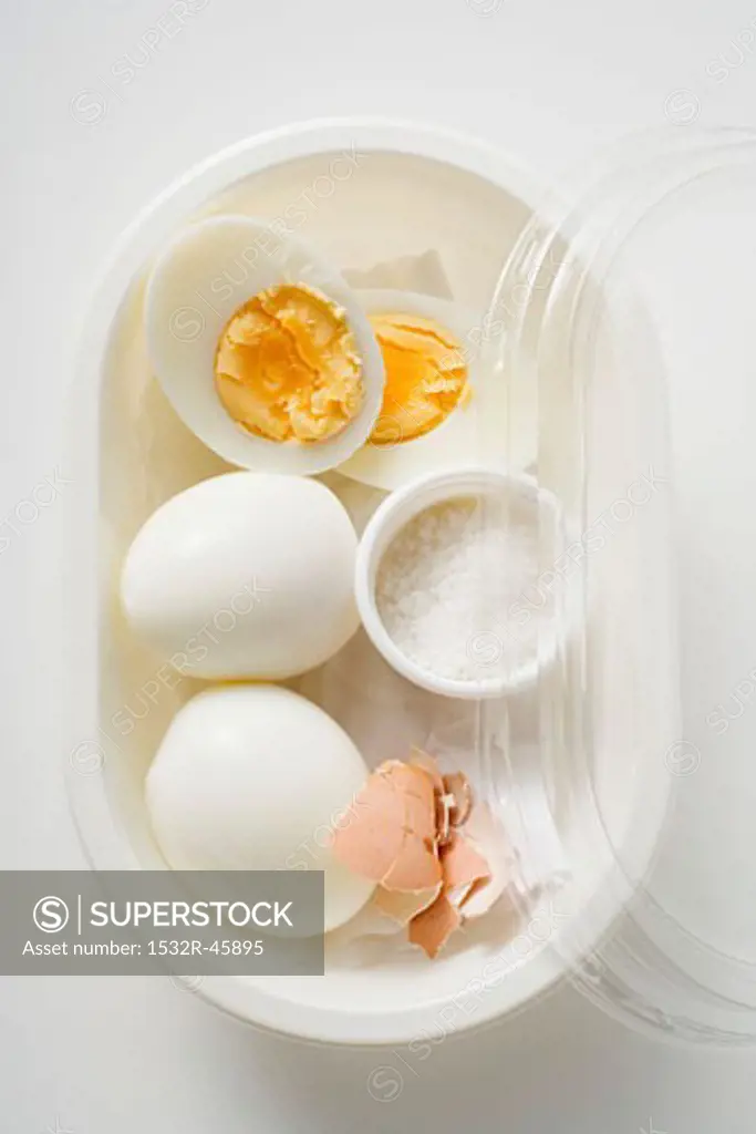 Boiled eggs and salt in plastic food storage container