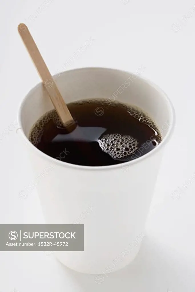 Black coffee in paper cup with wooden stirrer