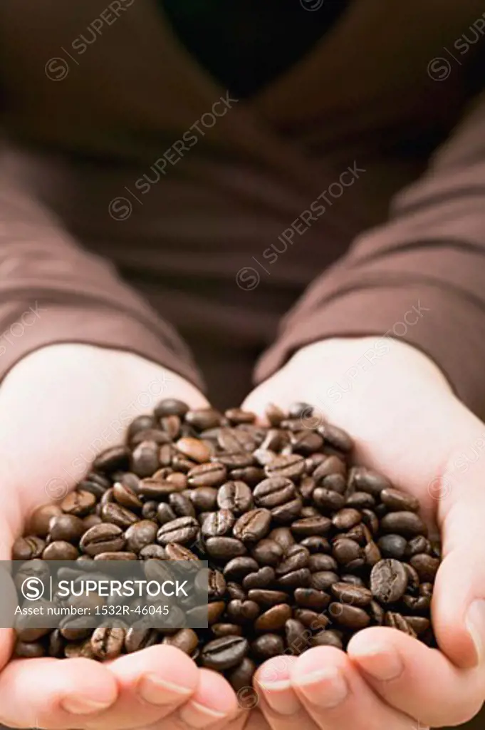 Hands holding a heap of coffee beans