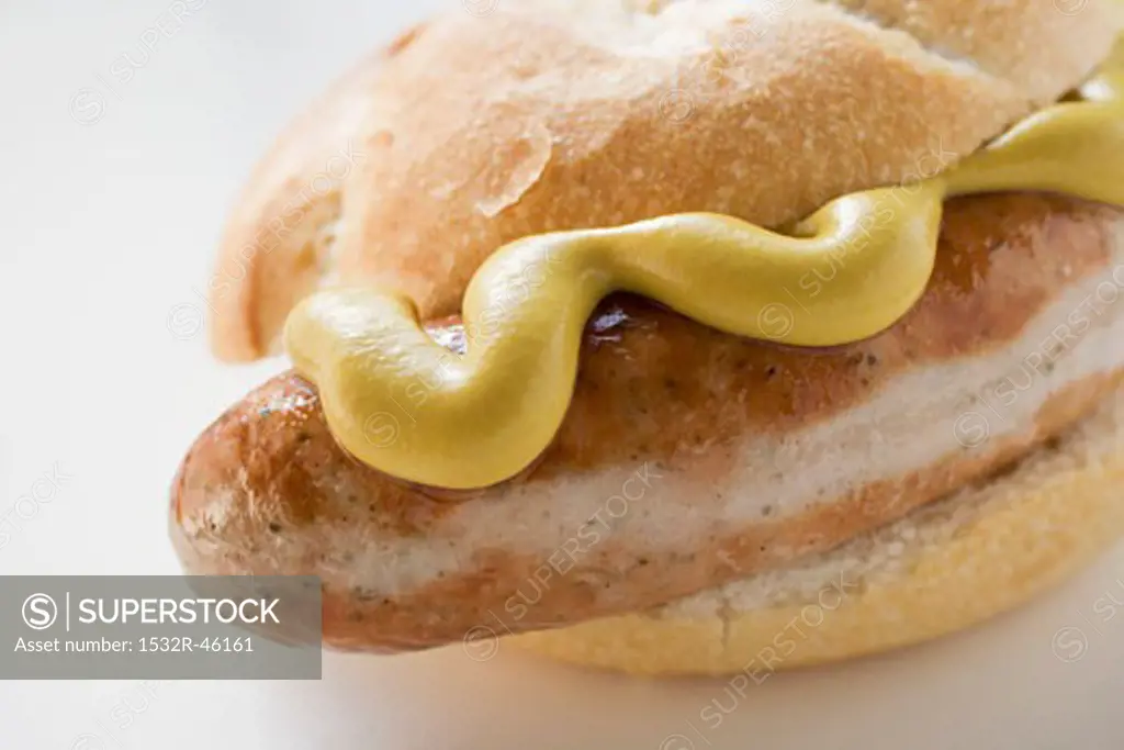 Sausage (bratwurst) with mustard in bread roll