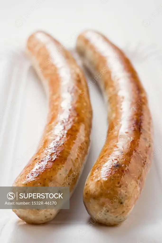 Two sausages (bratwursts) on paper plate