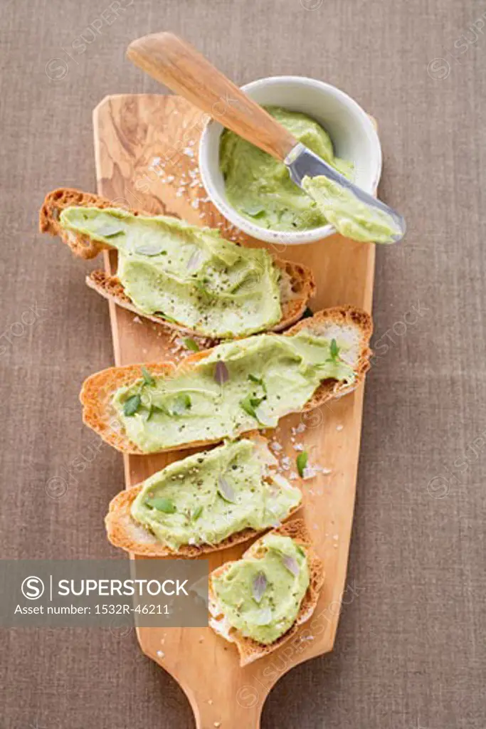 Bruschetta with avocado spread on chopping board (overhead)