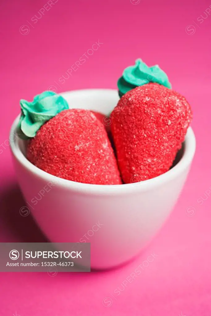 Sugar strawberries in small white bowl on red background