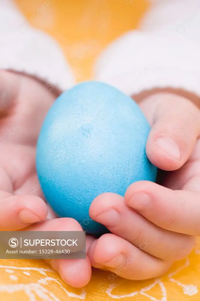 Child's hands holding a blue egg