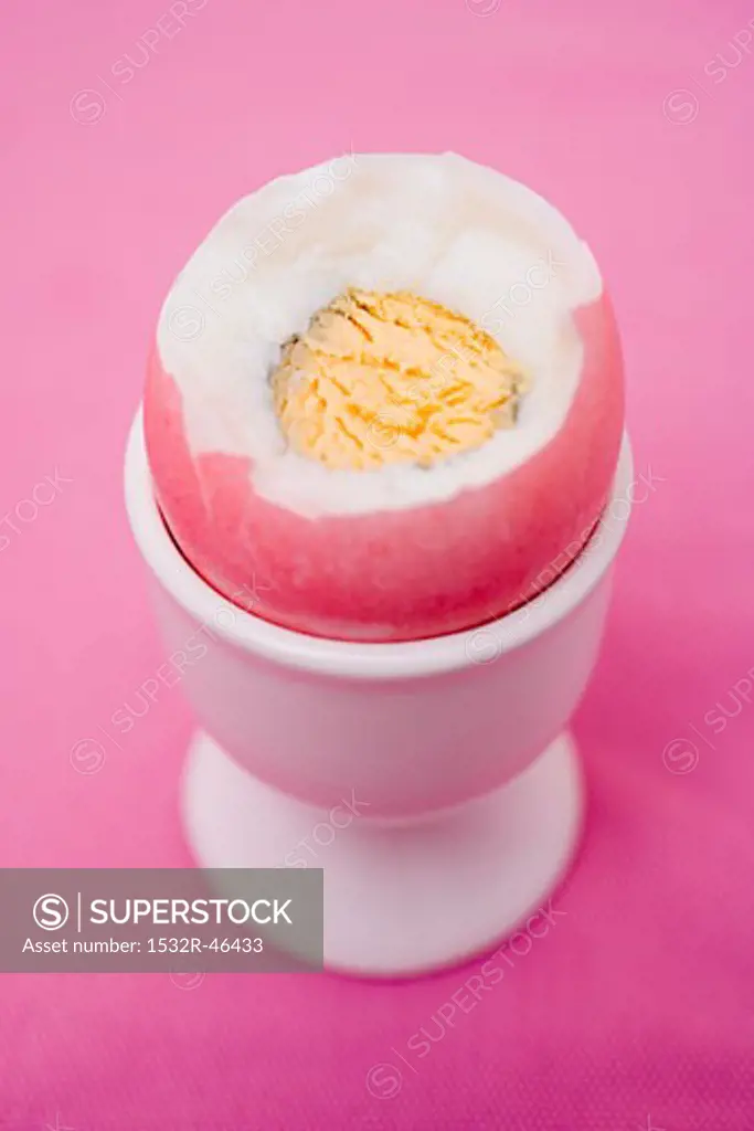 Coloured boiled egg in eggcup (with top cut off)