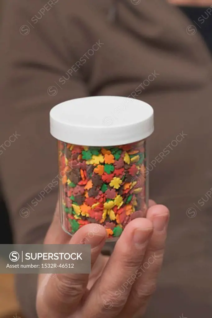 Hand holding a pot of sprinkles for Halloween