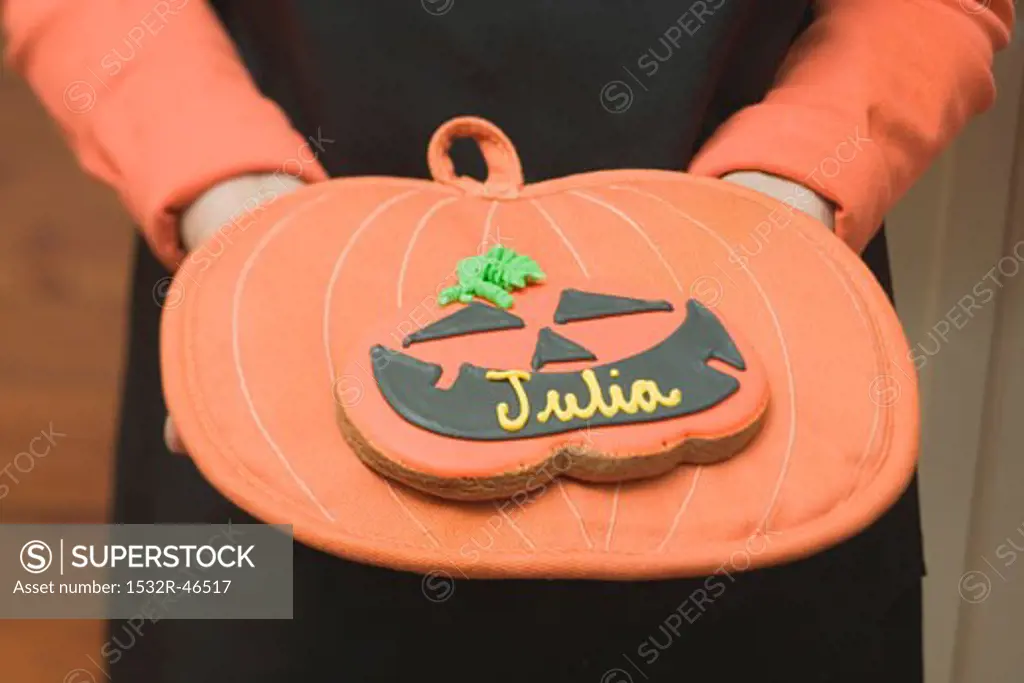 Hands holding Halloween biscuit with name on pot holder