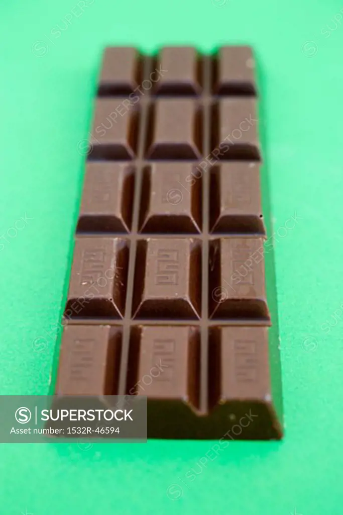 Bar of chocolate on green background