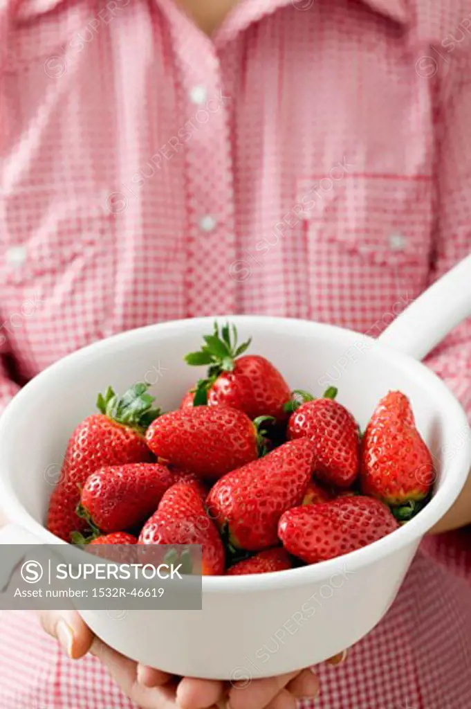 Woman holding strainer full of strawberries
