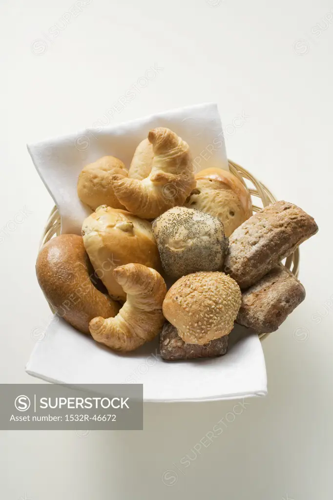 Bread rolls and croissants in bread basket (overhead view)