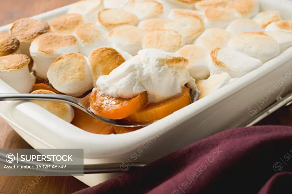 Sweet potato & marshmallow gratin in baking dish with spoon