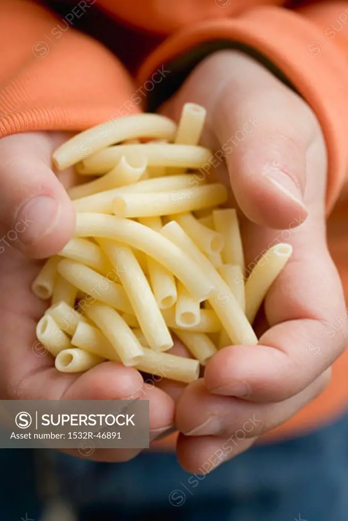 Child's hands holding macaroni