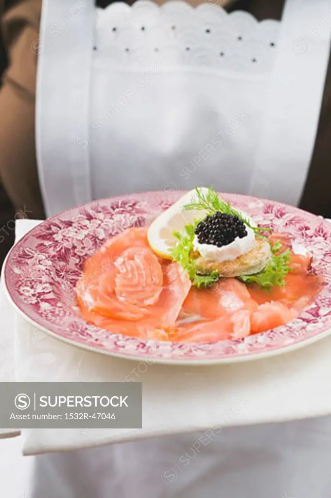 Chambermaid serving smoked salmon with caviar