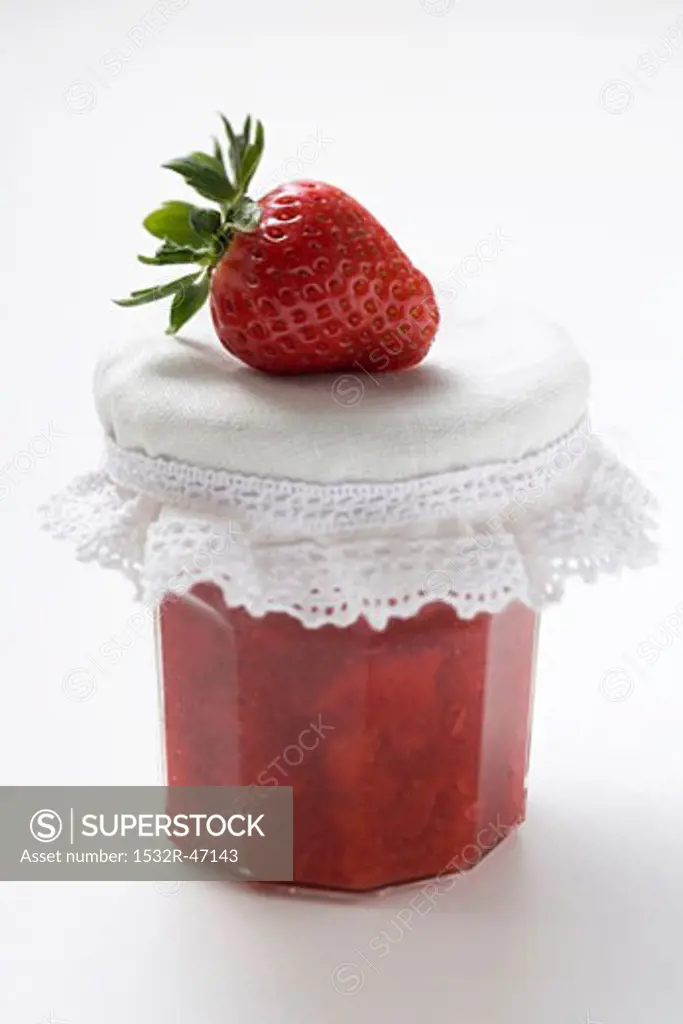 Jar of strawberry jam with a fresh strawberry