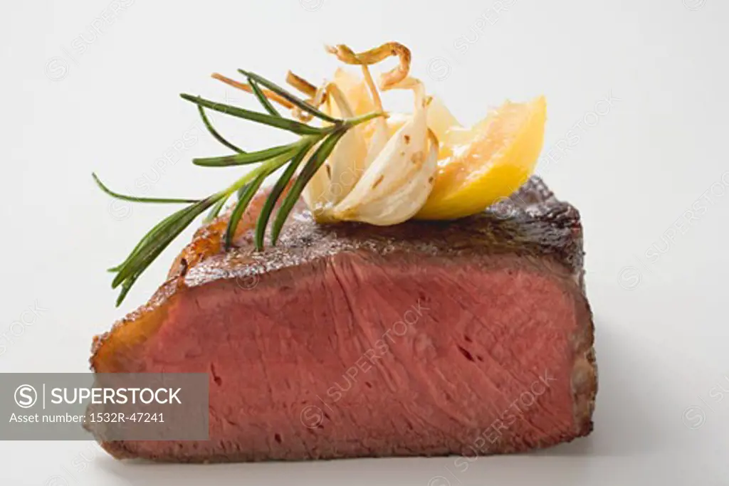 Beef steak, showing cut edge, with garlic, rosemary, lemon