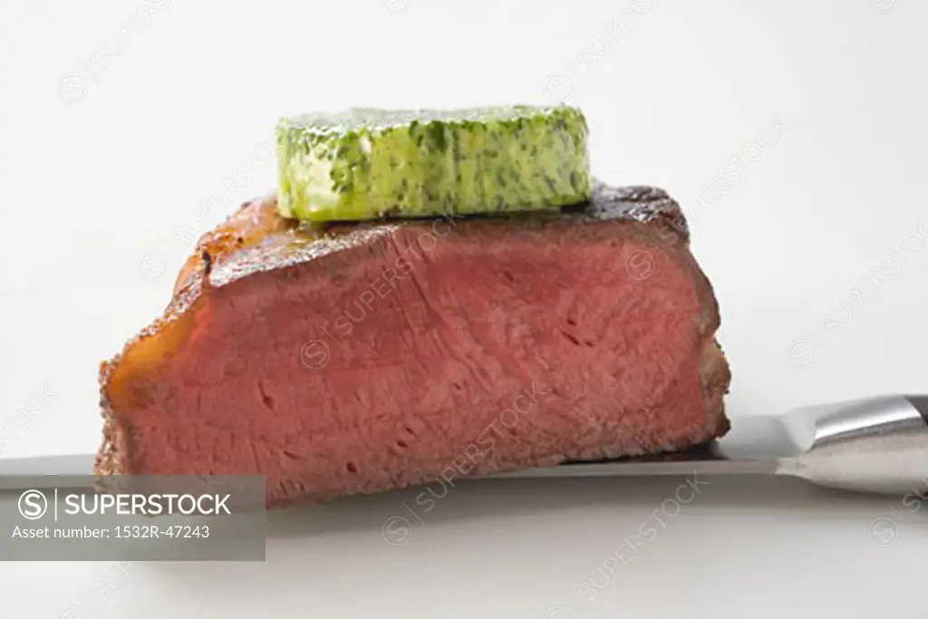 Beef steak with herb butter on knife (showing cut edge)