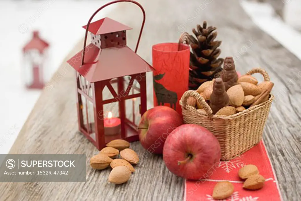 Christmas decoration with apples, nuts & lantern on table