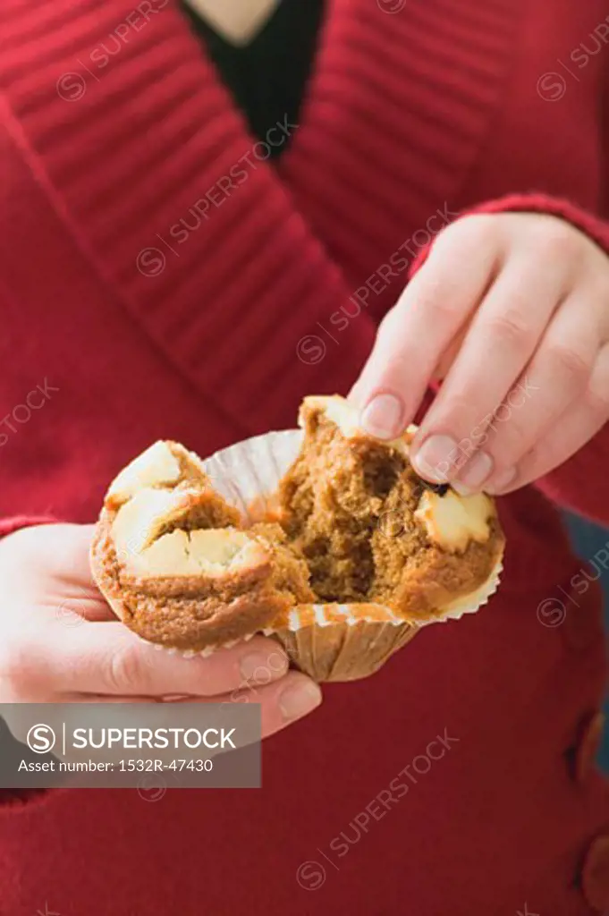 Woman halving a muffin in a paper case