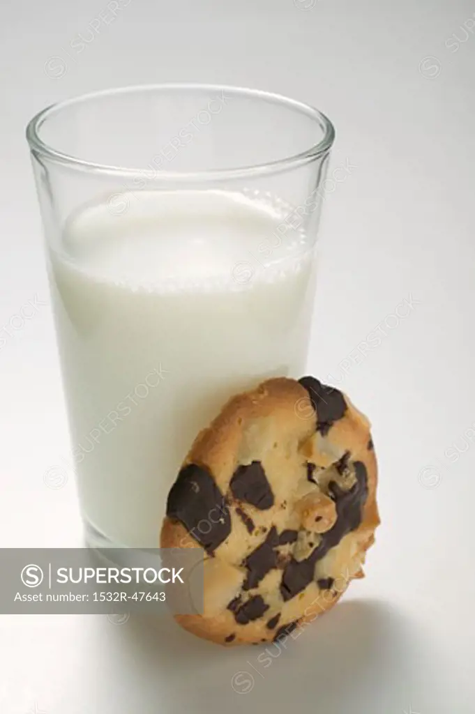 Chocolate chip peanut cookie beside glass of milk
