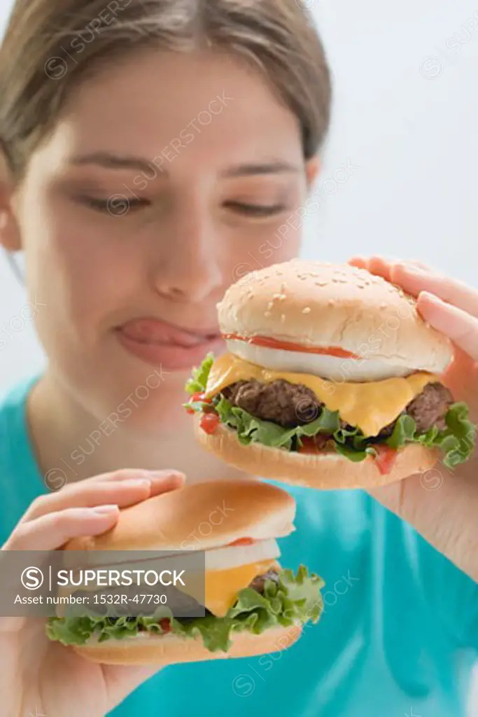Young woman holding two succulent cheeseburgers