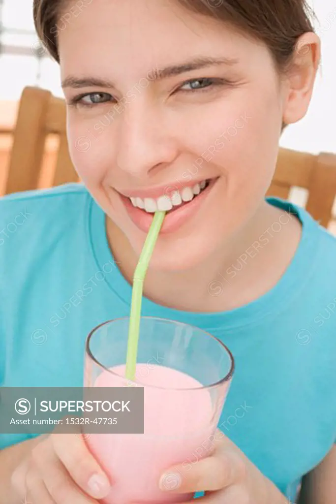 Young woman drinking strawberry milk through a straw