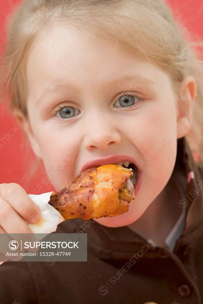 Little girl eating chicken drumstick