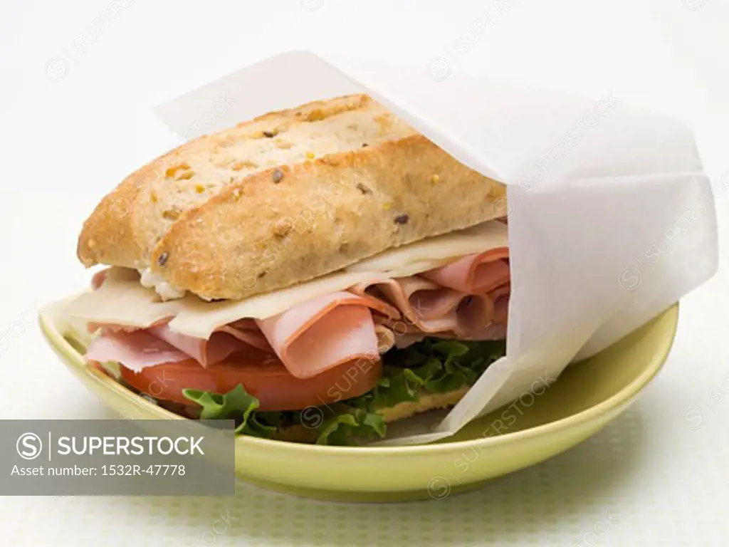 Ham, cheese, lettuce & tomato sandwich in greaseproof paper