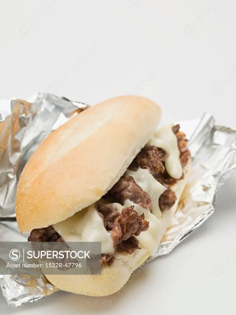 Shredded beef sandwich with melted cheese on aluminium foil