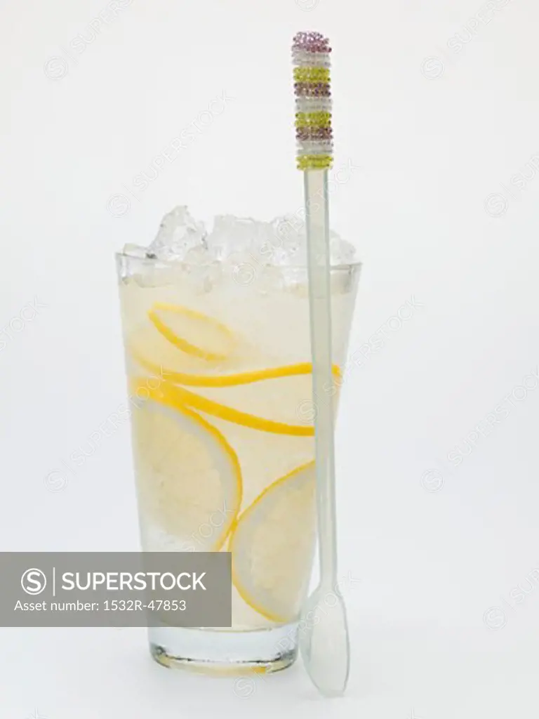 A glass of lemonade with crushed ice, spoon beside it