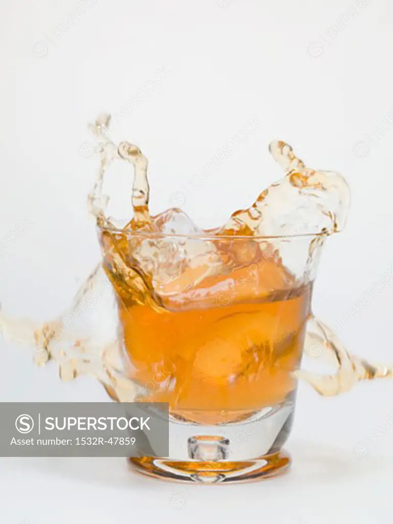 Ice cube falling into a glass of iced tea